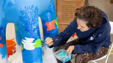 Artist painting a sculpture