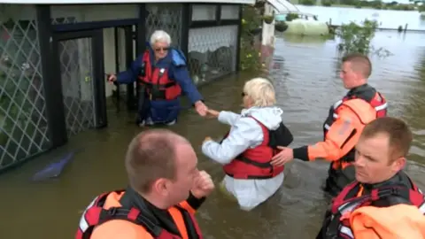 People being helped out of a house