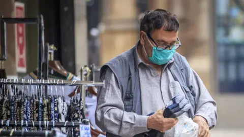 PA Media An Asian man with a mask in Bradford