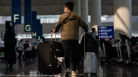 Getty Images A man wheels suitcases through an airport