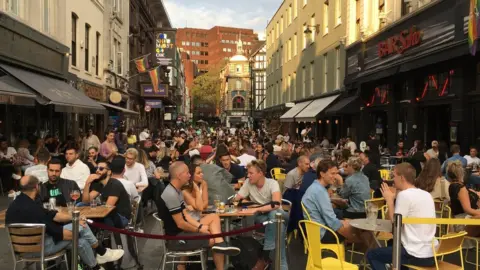 Simon Jones/BBC News People sit outside restaurants and bars in London's Soho district on Saturday 19 September 2020