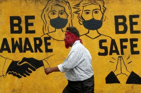 Reuters A man walks past a graffiti amid the spread of the coronavirus disease (COVID-19) in Mumbai, India, November 2, 2020.