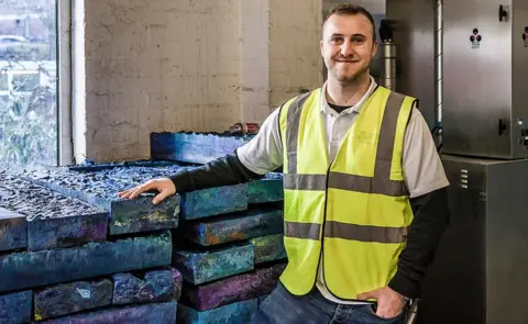 Thermal Compaction Group A Thermal Compaction Group worker standing in front of its blocks of recycled plastic