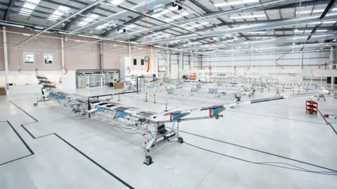 Phil Adams/Airbus A manufacturing floor with a long, transparent glider-like plane visible in the foreground