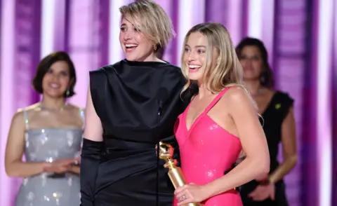 Getty Images Greta Gerwig and Margot Robbie accept the award for Cinematic and Box Office Achievement for "Barbie" at the 81st Golden Globe Awards held at the Beverly Hilton Hotel on January 7, 2024 in Beverly Hills, California