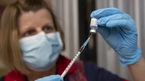 PA Media A nurse fills a syringe with a Covid vaccine