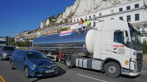 PA Media Protesters from Insulate Britain sit on top of a vehicle as they block the A20 in Kent