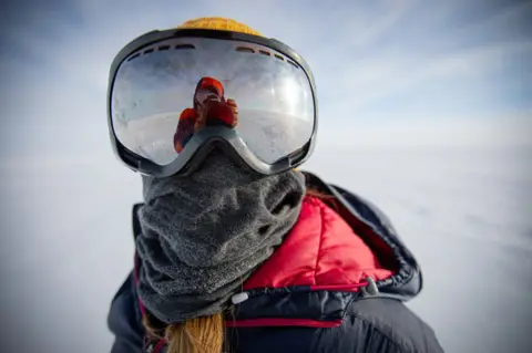 Ben Sadd Person wearing a large pair of goggles - in icy Antarctic landscape... also a warm coat and scarf