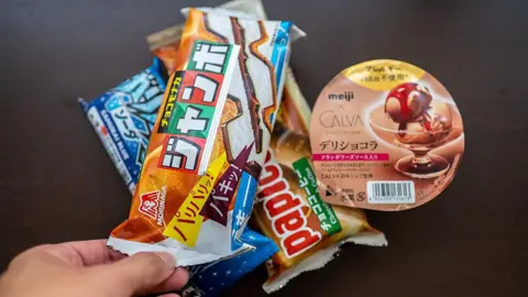 A hand holding several packages of ice cream sold in spermarkets and convenience stores in Japan