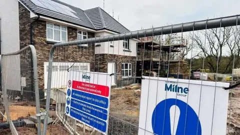 Construction site with a Stewart Milne sign and housebuilding work.