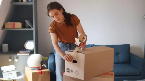 Getty Images: Woman packs boxes as she prepares to move