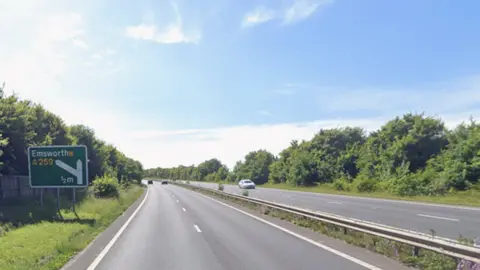 A27 dual carriageway with green road sign to Emsworth on the left verge.