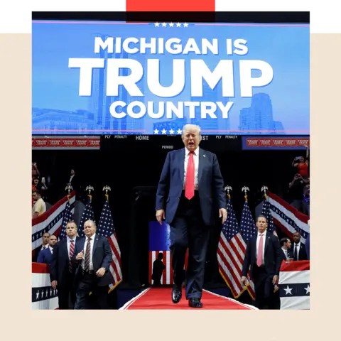 Donald Trump walks in front of a sign that reads 'Michigan is Trump country'