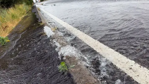 Cambridgeshire Constabulary Water overflowing on a road.