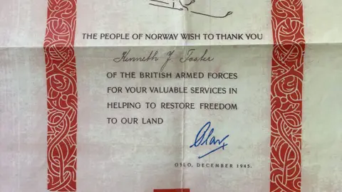 An old certificate with a red patterned border reading: 'The people of Norway wish to thank you Kenneth Foster of the British Armed Forces for your valuable services in helping to restore freedom to our land.' It is then signed in blue ink and dated December 1945.