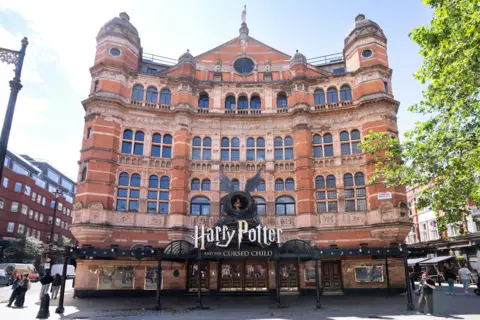 Getty Images Harry Potter and the Cursed Child sign with boy inside a nest with wings outside a red brick building