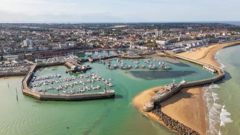An aerial image of a harbour on the coast of a large town