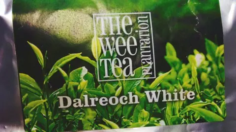 A label for tea showing green coloured tea plants. It bears the logo of the Wee Tea Plantation and the variety name Dalreoch White