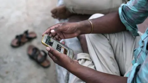 Bloomberg via Getty Images A man looks at WhatsApp messages on his mobile phone in Gadwal district of southern India's Telangana state on 11 June 2018 - a time when police across Indian states were struggling to stop rumours spread through the messaging app about "child kidnapping" which was triggering violence across states.