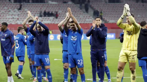 EPA Rangers players celebrate their 4-1 victory: several of the players, dressed in their uniform or training shirts, applaud the fans after the match.