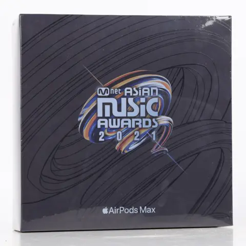 Bishop & Miller Auctioneers A general view of a sealed box of Apple's Airpods Max headphones. The square box is black and sealed. The logo of the M Net Asian Music Awards from 2021 is printed in the middle.