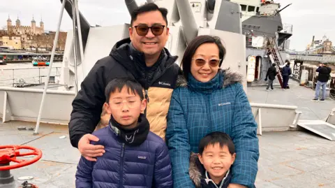 Lawrence Fong and his family stand in front of HMS Belfast