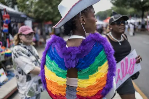 Marco Longari / AFP An attendee parades an outfit adorned with rainbow-colored wings during the 2024 edition of the Johannesburg Pride.