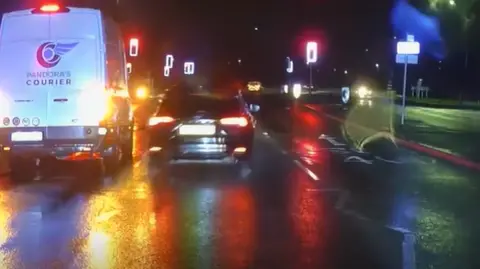 A black car overtaking a white van