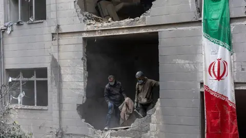 Getty Images People clear rubble in a house in the Beryanak District after it was damaged by missile attacks two days before, on March 15, 2026 in Tehran