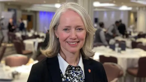 Deputy Kristina Moore is pictured in a hall with lots of tables behind her. 