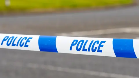 Blue and white police tape across a street 