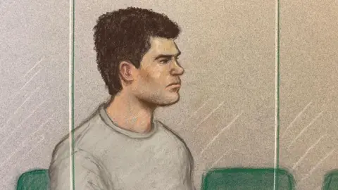 A court artist drawing of Jake Cummings - he has short dark hair, is wearing a grey, round-neck top and sitting on a green chair behind the glass in the dock of a courtroom
