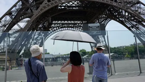  Tourists arrive at a closed Eiffel tower during a heat wave