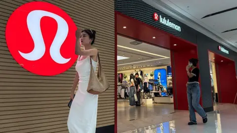 A woman in a white dress walks past a Lululemon store with its signature red logo displayed prominently on the wall, as shoppers browse inside the store, on 4 June, 2025 in Chongqing, China.