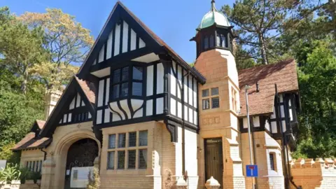 The Grade II listed St Mary's Lodge with a yellow ground floor exterior and upper floors partially white and black on the outside.