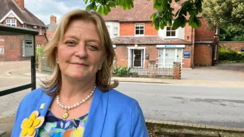 Female campaigner stands outside the Barclays Bank branch in Leiston