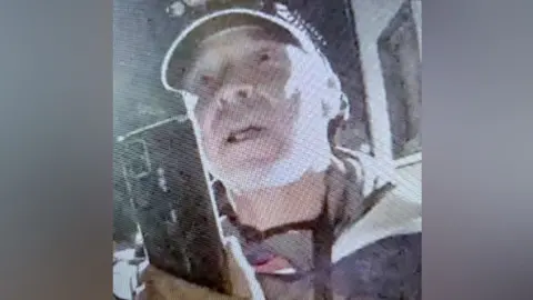 A grainy image of Gavin Turpie, a man with a baseball cap on.