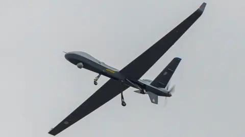 RAF A grey and black Protector drone flying through the sky against a grey background.