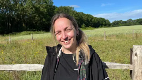 Senior Participation Officer Camile McCawley leans against a wooden paddock fence at  Ranscombe Farm Nature Reserve