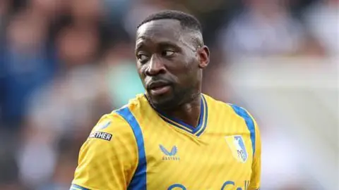 A close up of a football player wearing a yellow shirt with blue logos.