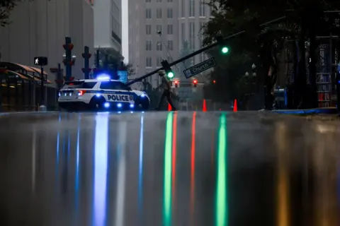 Jose Luis Gonzalez / Reuters A view shows light falling over a wet street with a fallen traffic light near a police car in the background in Orlando, Florida, U.S., October 10, 2024