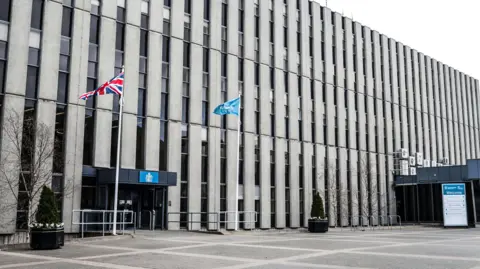 The outside of the Darlington council building. It is a large concrete building with two flag poles outside.