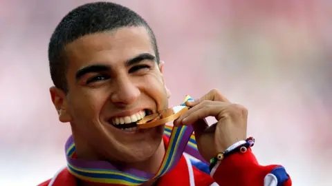 Getty Images Adam Gemili biting a gold medal.
