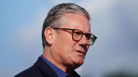 PA Media Sir Keir Starmer stood in front of a wind turbine in a field in Carmarthenshire