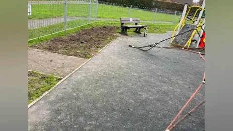 A play area with paw prints and mud and dog faeces on the floor