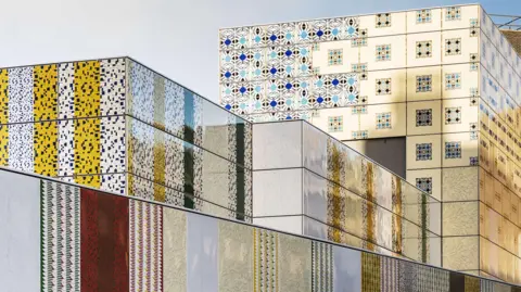 Thierry Bal The outside of a Tube station with large rooftop blocks wrapped in an enamel covering with various patterns reminiscent of Middle Eastern designs, in blue, black, white and yellow. 