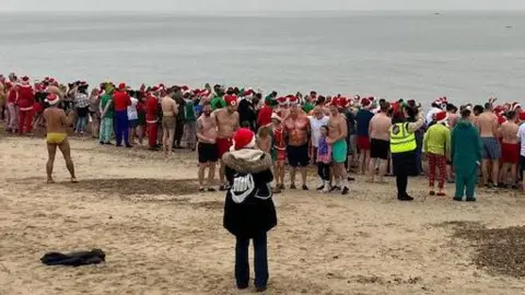 Alison Root/BBC People lining the Felixstowe shoreline before entering the North Sea