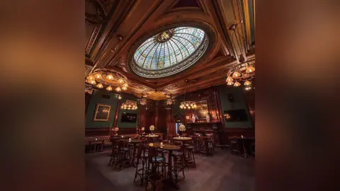 1936 Pubco Interior of the plush neo-Baroque designed pub with carved mahogany woodwork throughout, repousse copper panels, and a stained-glass dome.