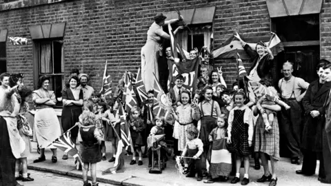 PA British men, women and children celebrating Victory in Europe Day in the street in London, 8 May, 1945.