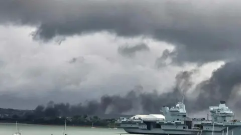 Katherine Floyd A large cloud of smoke hovering over a marina